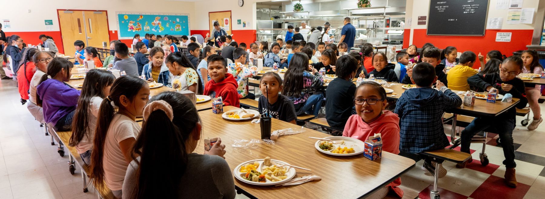 A large group of students enjoying lunch together in a busy cafeteria.