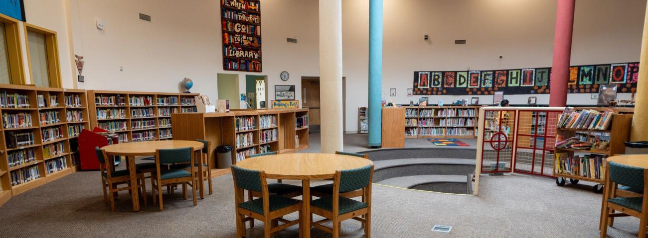 A school library filled with tables and chairs, perfect for studying and reading in a quiet space.